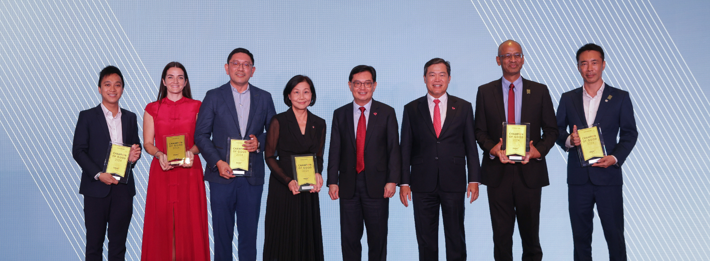 Eight people in suits and formal wear hold "Champion of Good 2024" awards on a patterned blue background.